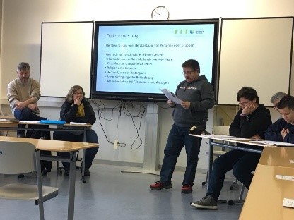 Seminarsituation. Eine Person liest aus Buch vor.